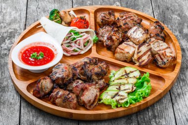 Çeşitli lezzetli ızgara et ve sebze taze salata ve kesme tahtası üzerinde ahşap arka plan barbekü sosu ile kapatın. Sıcak et yemekleri. Üstten Görünüm