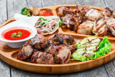 Çeşitli lezzetli ızgara et ve sebze taze salata ve kesme tahtası üzerinde ahşap arka plan barbekü sosu ile kapatın. Sıcak et yemekleri. Üstten Görünüm