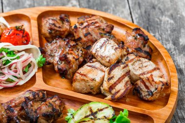 Çeşitli lezzetli ızgara et ve sebze taze salata ve kesme tahtası üzerinde ahşap arka plan barbekü sosu ile kapatın. Sıcak et yemekleri. Üstten Görünüm
