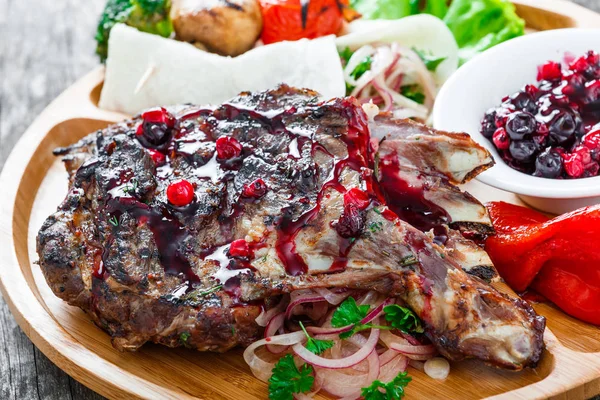 Grilled Ribeye Steak on bone with berry sauce, fresh salad and grilled vegetables on cutting board on wooden background close up. Hot Meat Dishes — Stock Photo, Image