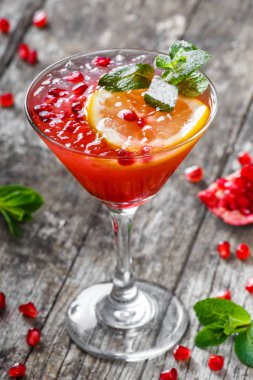 Taze meyve kokteyli nane, nar, limon cam ahşap arka plan üzerinde kırmızı. Yaz içecekler ve alkollü kokteyller.