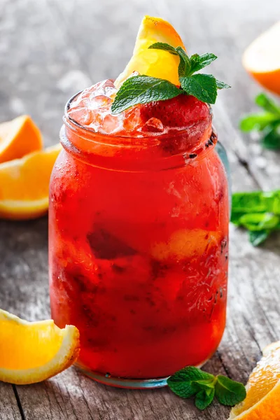 Fresh red strawberry lemonade with mint, orange and ice in glass jar on wooden background. Summer drinks and cocktails. — Stock Photo, Image