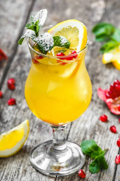 Fresh fruit tropic cocktail with mint, lemon and pomegranate in glass on wooden background. Summer drinks and alcoholic cocktails. — Stock Photo, Image