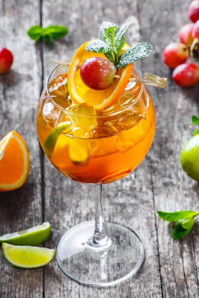 Cóctel tropical fresco con menta, naranja y lima en vaso alto sobre fondo de madera. Bebidas de verano y cócteles alcohólicos . — Foto de Stock