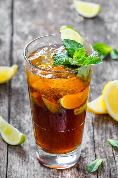 Cold cola with mint, lime and ice in glass on wooden background. Summer drinks and alcoholic cocktails. — Stock Photo, Image