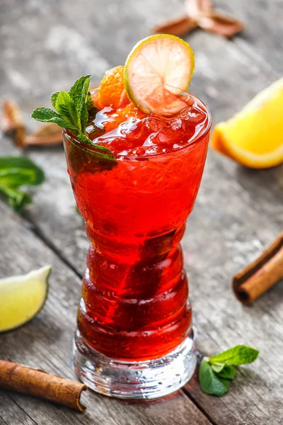 Cold fresh red lemonade with mint, orange, cinnamon and ice in glass on wooden background. Summer drinks and alcoholic cocktails. — Stock Photo, Image