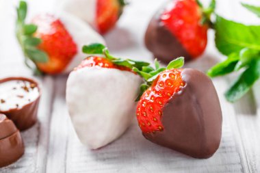Taze çilek ışık arka plan üzerinde koyu ve beyaz çikolata daldırma kapatın. Lezzetli tatlı ve şeker çubuğu. Üstten Görünüm