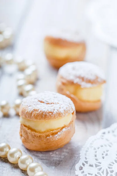 Profiterole ou bolos de puff de creme preenchidos com chantilly no fundo de madeira perto. Deliciosa sobremesa com decoração. Vista superior — Fotografia de Stock