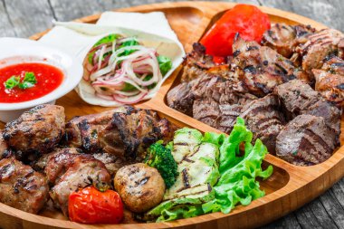 Çeşitli lezzetli ızgara et ve sebze taze salata ve kesme tahtası üzerinde ahşap arka plan barbekü sosu ile kapatın. Sıcak et yemekleri. Üstten Görünüm
