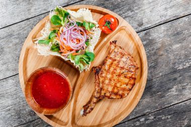 Izgara dana biftek kemik, taze salata, ızgara sebzeler ve kesme tahtası ahşap zemin üzerine domates sosu. Sıcak et yemekleri. Üstten Görünüm