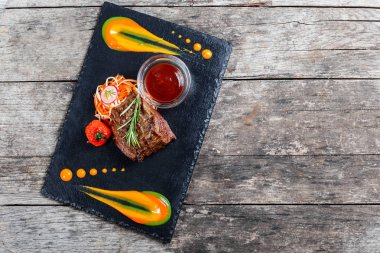 Taze salata ve Barbekü sos ahşap arka plan üzerinde taş arduvaz arka plan üzerinde ızgara sığır eti biftek kapatın. Sıcak et yemekleri. Üstten Görünüm