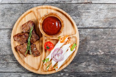Izgara et ve sebze taze salata ve kesme tahtası üzerinde ahşap arka plan barbekü sosu ile kapatın. Sıcak et yemekleri. Üstten Görünüm