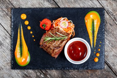 Taze salata ve Barbekü sos ahşap arka plan üzerinde taş arduvaz arka plan üzerinde ızgara sığır eti biftek kapatın. Sıcak et yemekleri. Üstten Görünüm