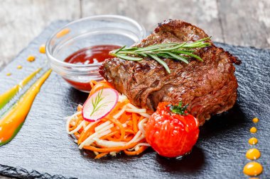 Taze salata ve Barbekü sos ahşap arka plan üzerinde taş arduvaz arka plan üzerinde ızgara sığır eti biftek kapatın. Sıcak et yemekleri. Üstten Görünüm