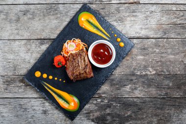 Taze salata ve Barbekü sos ahşap arka plan üzerinde taş arduvaz arka plan üzerinde ızgara sığır eti biftek kapatın. Sıcak et yemekleri. Üstten Görünüm