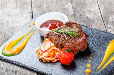 Taze salata ve Barbekü sos ahşap arka plan üzerinde taş arduvaz arka plan üzerinde ızgara sığır eti biftek kapatın. Sıcak et yemekleri. Üstten Görünüm