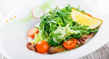 Deniz ürünleri salatası midye, mürekkep, ahtapot, roka, marul ve domates ahşap zemin üzerine kapatın. Akdeniz yemekleri