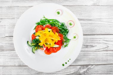 Taze salata domates, salatalık, turp, tatlı biber ve soğan bir plaka üzerinde ahşap arka plan ile kapatın. Üstten Görünüm