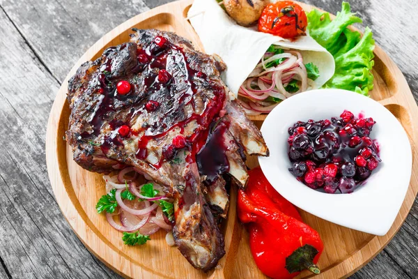 Grilovaná Ribeye Steak na kosti s berry omáčka, čerstvý salát a grilované zeleniny na prkénku na dřevěné pozadí zblízka. Horká masová jídla — Stock fotografie