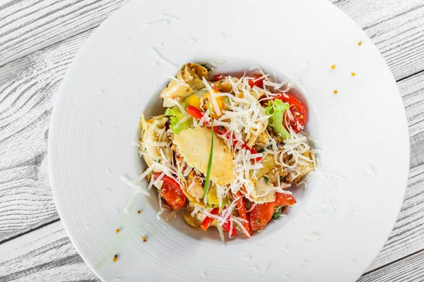 Salada fresca com peito de frango, alcachofras, tomate cereja, alface e queijo parmesão em fundo de madeira perto. Vista superior — Fotografia de Stock