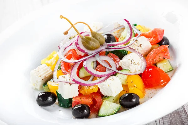 Griechischer Salat mit frischem Gemüse, Oliven und Feta-Käse auf hölzernem Hintergrund in Großaufnahme. Ansicht von oben — Stockfoto