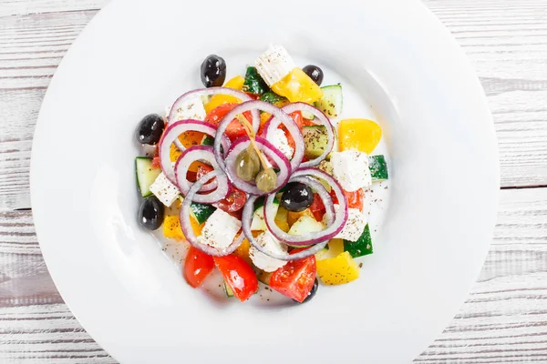 Greek salad with fresh vegetables, olives and feta cheese on wooden background close up. Top view — Stock Photo, Image