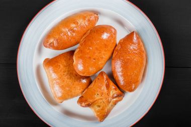 Taze ekmek buns pies köftesi plaka siyah ahşap zemin üzerine. Pastane. Sıcak ve sağlıklı kahvaltı, üstten görünüm, düz yatıyordu