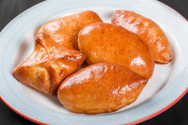 Taze ekmek buns pies köftesi plaka siyah ahşap zemin üzerine. Pastane. Sıcak ve sağlıklı kahvaltı, üstten görünüm, düz yatıyordu