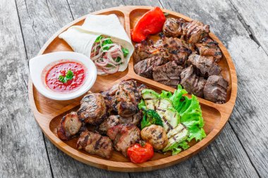 Çeşitli lezzetli ızgara et ve sebze taze salata ve kesme tahtası üzerinde ahşap arka plan barbekü sosu ile kapatın. Sıcak et yemekleri. Üstten Görünüm