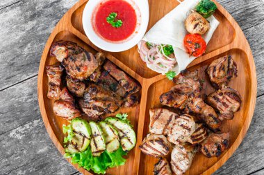 Çeşitli lezzetli ızgara et ve sebze taze salata ve kesme tahtası üzerinde ahşap arka plan barbekü sosu ile kapatın. Sıcak et yemekleri. Üstten Görünüm