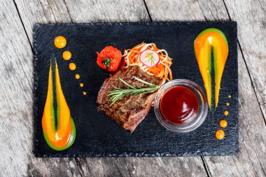 Taze salata ve Barbekü sos ahşap arka plan üzerinde taş arduvaz arka plan üzerinde ızgara sığır eti biftek kapatın. Sıcak et yemekleri. Üstten Görünüm