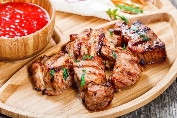 Cerdo a la parrilla y verduras con ensalada fresca y salsa barbacoa en la tabla de cortar sobre fondo de madera de cerca. Platos de carne caliente. Vista superior —  Fotos de Stock