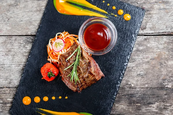 Taze salata ve Barbekü sos ahşap arka plan üzerinde taş arduvaz arka plan üzerinde ızgara sığır eti biftek kapatın. Sıcak et yemekleri. Üstten Görünüm