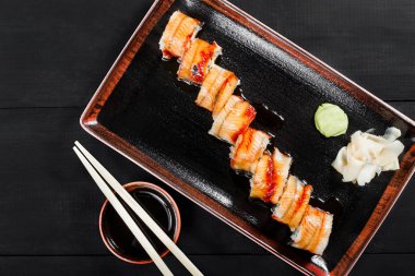 Suşi Roll - füme yılan balığı ile Maki Sushi, koyu ahşap zemin üzerine salatalık, avokado ve krem peynir. Üstten Görünüm. Japon mutfağı