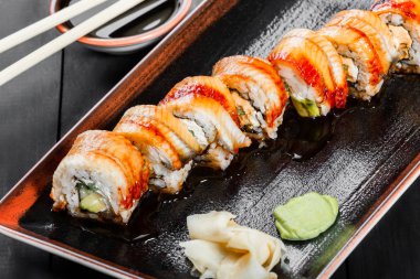 Suşi Roll - füme yılan balığı ile Maki Sushi, koyu ahşap zemin üzerine salatalık, avokado ve krem peynir. Üstten Görünüm. Japon mutfağı