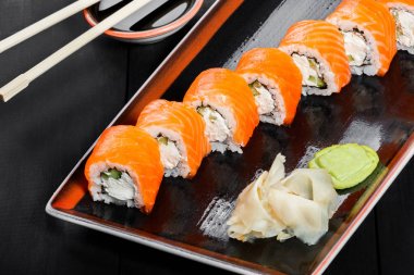 Suşi Roll - somon, salatalık, avokado ve krem peynir koyu ahşap arka plan üzerinde Maki Sushi yapılmış. Üstten Görünüm. Japon mutfağı