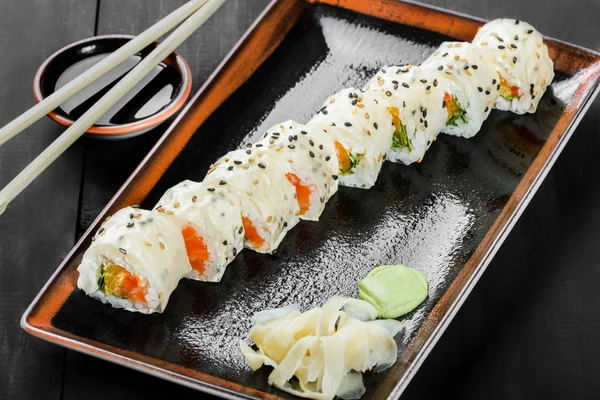 Sushi Roll - Maki Sushi made of salmon, orange, avocado and cream cheese on dark wooden background. Top view. Japanese cuisine