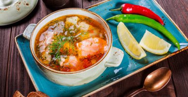 Balık çorbası ile somon ve karides, dereotu, patates, limon, biber ve koyu ahşap arka plan, sağlıklı yiyecek ekmek. Üstten Görünüm