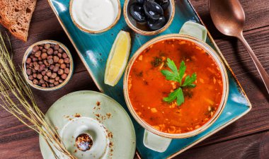 Et, zeytin, otlar, limon, kase, siyah ekmek ve koyu ahşap zemin, ev yapımı yiyecek üzerine baharat ekşi krema çorbası. Geleneksel Rus çorbası - solyanka. Üstten Görünüm