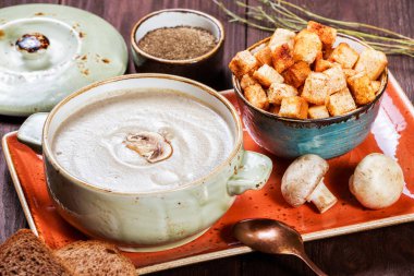 Mantar, otlar, krem ve kraker koyu ahşap arka plan üzerinde plaka üzerinde krem çorbası. Ev yapımı yemek. Maddeler tablosundaki. Üstten Görünüm