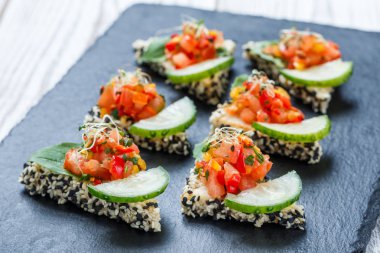 Meze kanepe doğranmış sebze ve susam kayrak taş zemin üzerine kapatın. Lezzetli aperatifler, sandviçler, crostini, bruschetta, parti ya da piknik zamanında antipasti. Üstten Görünüm