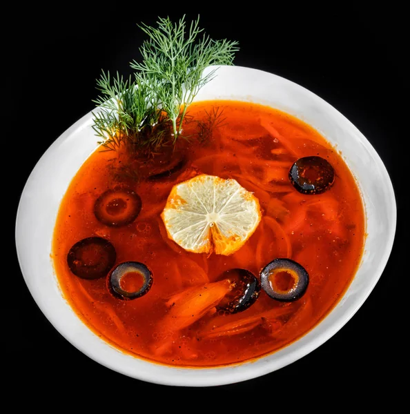 Sopa con carne, aceitunas, hierbas y limón en tazón, aislado sobre fondo negro, comida casera. La sopa tradicional rusa - solyanka — Foto de Stock