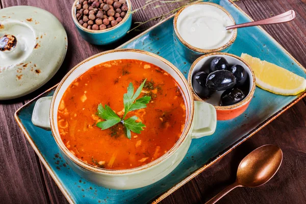 Et, zeytin, otlar, limon, kase, siyah ekmek ve koyu ahşap zemin, ev yapımı yiyecek üzerine baharat ekşi krema çorbası. Geleneksel Rus çorbası - solyanka. Üstten Görünüm