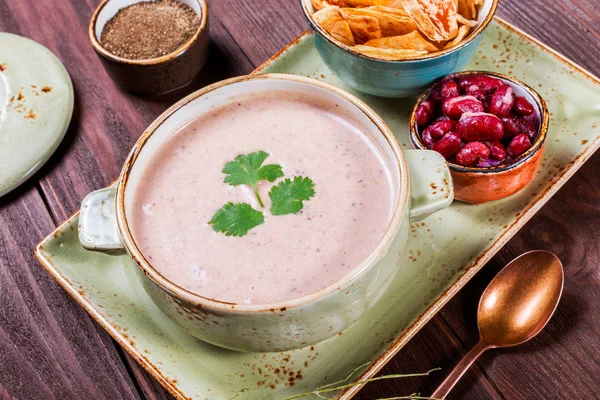 Sopa de crema con frijoles, verduras, hierbas y galletas en el plato sobre fondo de madera oscura. Comida casera. Ingredientes en la mesa —  Fotos de Stock