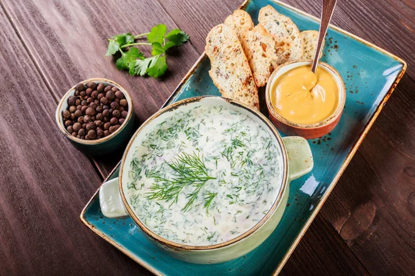 Sopa fria ou iogurte de verão com rabanete, pepino, endro, ervas e biscoitos no fundo de madeira escura. Okroshka. Comida caseira. Ingredientes na mesa. Vista superior — Fotografia de Stock