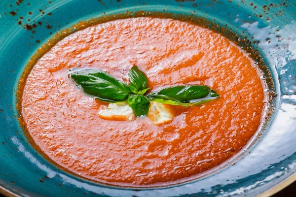 Sopa de gazpacho de tomate en tazón con albahaca, queso feta, hielo sobre fondo de madera oscura, cocina española. Vista superior —  Fotos de Stock