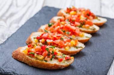Meze bruschetta ciabatta ekmeği kayrak taş zemin üzerine doğranmış sebze ile kapatın. Lezzetli aperatifler, sandviçler, crostini, kanepe, parti ya da piknik zamanında antipasti. Üstten Görünüm