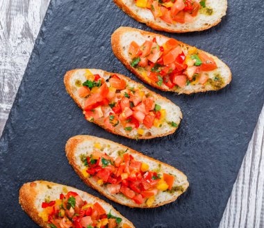 Meze bruschetta ciabatta ekmeği kayrak taş zemin üzerine doğranmış sebze ile kapatın. Lezzetli aperatifler, sandviçler, crostini, kanepe, parti ya da piknik zamanında antipasti. Üstten Görünüm