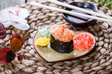 Suşi Gunkan maki ile bambu hasır tabağa somon çiçeklerle süslenmiş. Japon mutfağı. Seçici odak