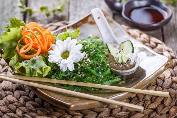 Yosun Salata wakame plaka ile chopsticks bambu hasır üzerinde. Japon mutfağı - sağlıklı deniz ürünleri — Stok fotoğraf